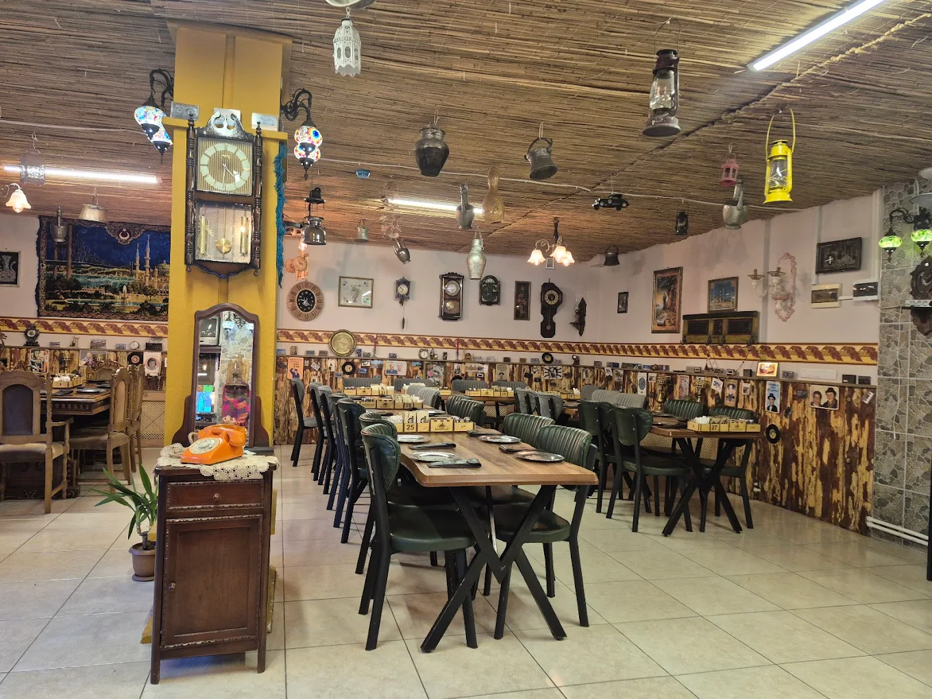 Nostaljik dekorlu salon: sarı sütun, antika duvar saati, kilimler ve hasır tavan